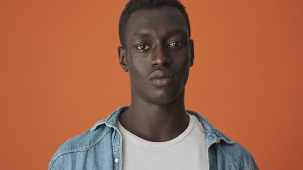 Nærbilde Smilende Afroamerikansk Ung Mann Ser Mot Kameraet Isolert Oransje – stockvideo