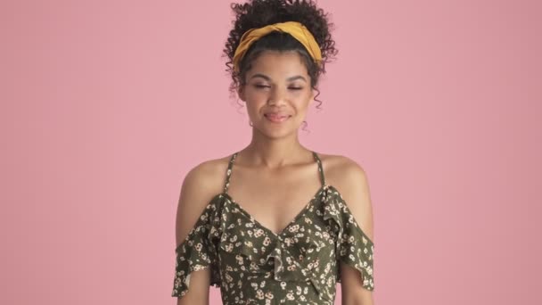 一位美丽的非洲裔美国年轻女子站在粉红的背景上做打招呼手势 — 图库视频影像
