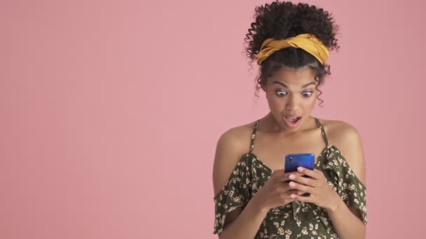 Una Joven Afroamericana Emocional Está Utilizando Teléfono Inteligente Mientras Mira — Vídeo de stock