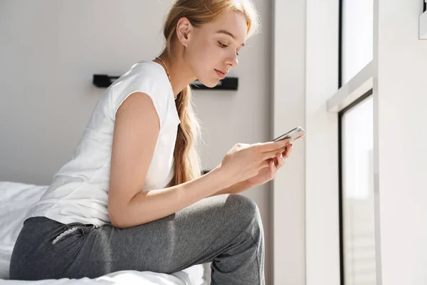 Foto Una Joven Enfocada Usando Teléfono Celular Mientras Está Sentada — Foto de Stock