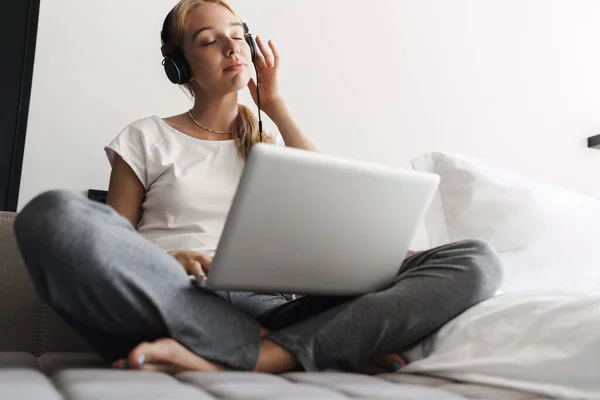 Foto Mujer Joven Tranquila Usando Auriculares Portátil Mientras Está Sentado —  Fotos de Stock