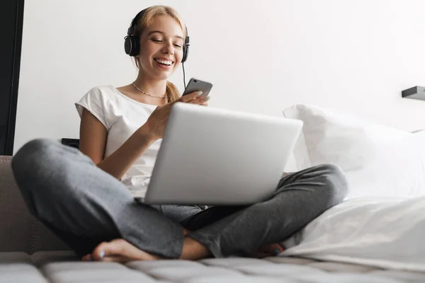 Foto Una Joven Alegre Que Usa Auriculares Teléfonos Celulares Mientras —  Fotos de Stock