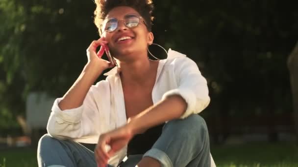 Μια Ενθουσιασμένη Νεαρή Αφροαμερικανή Γυαλιά Μιλάει Στο Smartphone Της Ενώ — Αρχείο Βίντεο