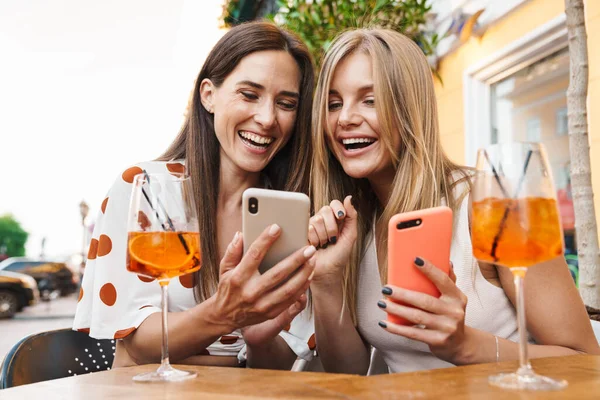 Kafede Kokteyl Içerken Gülümseyen Cep Telefonu Kullanan Iki Kadının Görüntüsü — Stok fotoğraf