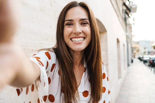 Neşeli, güzel bir kadının, kenar mahallede yürürken fotoğrafını çekip gülümsemesi.