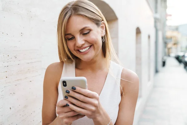 Imagem Mulher Loira Feliz Sorrindo Usando Telefone Celular Enquanto Caminha — Fotografia de Stock