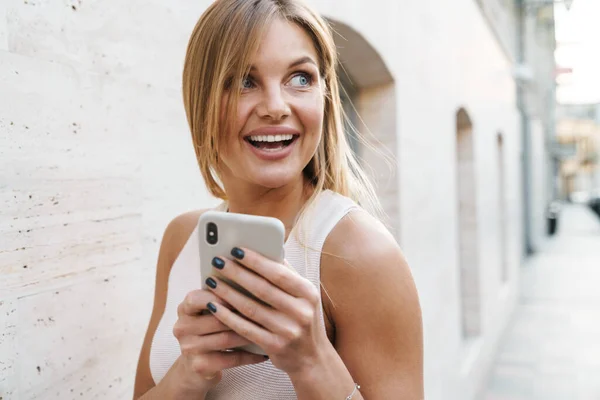 Imagem Mulher Loira Feliz Sorrindo Usando Telefone Celular Enquanto Caminha — Fotografia de Stock