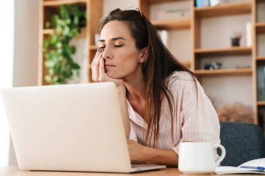 Ofiste otururken dizüstü bilgisayarla çalışan yorgun yetişkin iş kadını görüntüsü