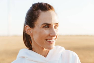 Altın tarlada çalışırken gülümseyen ve yan bakan güzel sporcu kadın görüntüsü