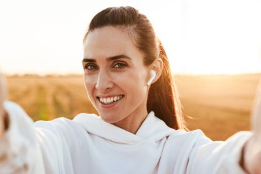 Golden Field 'da çalışırken kulaklık takan ve selfie çeken mutlu bir sporcu resmi.