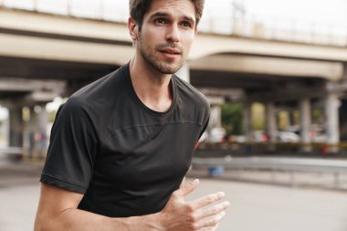 Şehir sokaklarında spor yaparken koşan atletik genç sporcunun görüntüsü