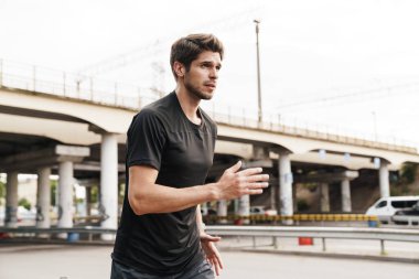 Şehir sokaklarında spor yaparken koşan atletik genç sporcunun görüntüsü