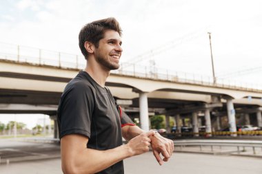 Atletik gülümseyen sporcunun şehir sokaklarında spor yaparken akıllı kaset kullanması