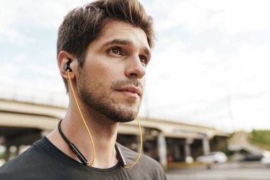 Atletik Kafkas sporcusunun şehir sokaklarında çalışırken kulaklık kullanması