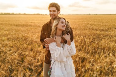 Kırsalda altın tarlada sarılan beyaz güzel bir çiftin görüntüsü.