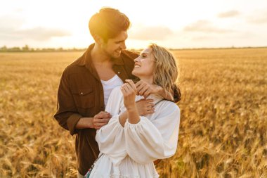 Kırsalda altın tarlada sarılan beyaz güzel bir çiftin görüntüsü.