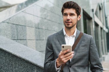 İş merkezinin yakınında cep telefonu kullanan ciddi anlamda yakışıklı bir iş adamının görüntüsü