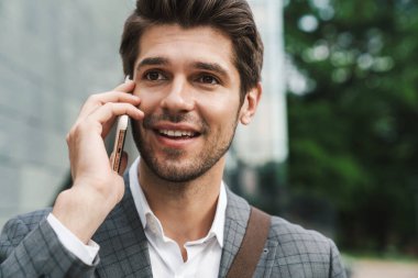 Neşeli iş adamının dışarıda cep telefonuyla konuşması.