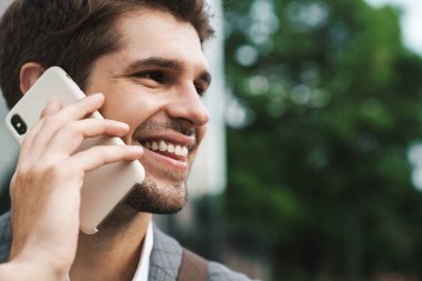 Neşeli iş adamının dışarıda cep telefonuyla konuşması.