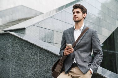 Dışarıda cep telefonu kullanan yakışıklı bir iş adamının resmi.