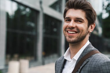Neşeli gülümseyen yakışıklı iş adamının görüntüsü iş merkezinin yakınında.