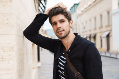 Sokakta yürüyen yakışıklı bir iş adamının fotoğrafı.