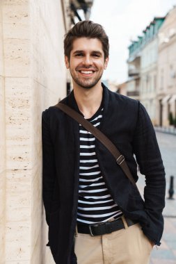 Sokakta yürüyen neşeli bir iş adamının fotoğrafı.