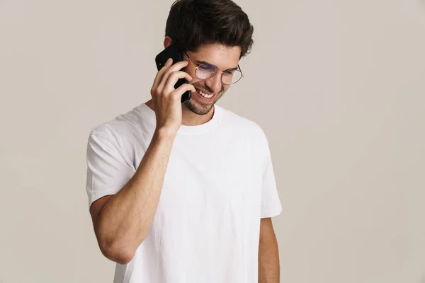 Gözlüklü Gülümseyen Genç Adamın Bej Arka Planda Cep Telefonuyla Konuşurken — Stok fotoğraf
