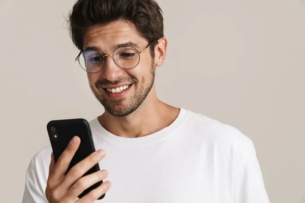 Bild Leende Ung Man Glasögon Skriva Mobiltelefon Isolerad Beige Bakgrund — Stockfoto