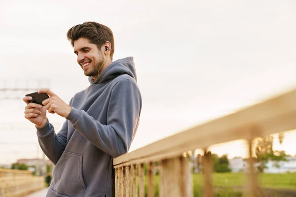 Bild Leende Man Med Hörlurar Som Spelar Dataspel Mobilen Medan — Stockfoto