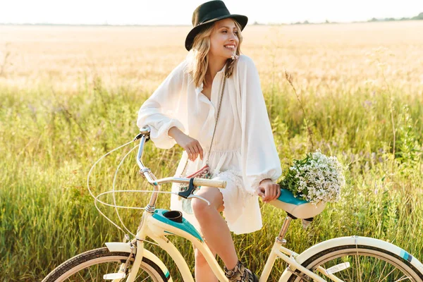 Imagem Jovem Loira Sorrindo Segurando Flores Enquanto Andava Bicicleta Campo — Fotografia de Stock