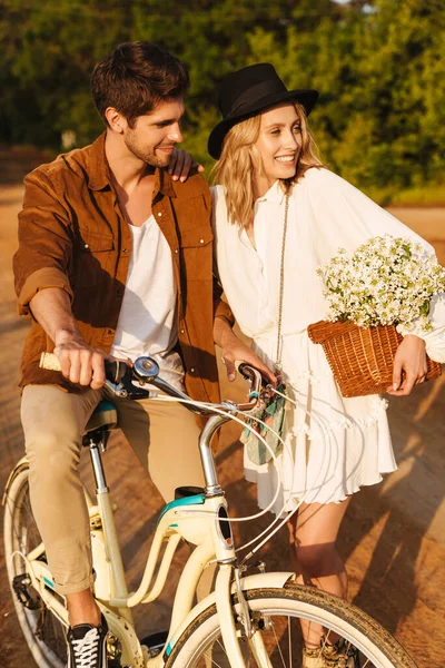 Image Young Caucasian Couple Smiling Holding Flowers While Riding Bicycle — Stock Photo, Image