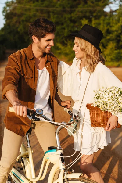 Image Young Caucasian Couple Smiling Holding Flowers While Riding Bicycle — Stock Photo, Image