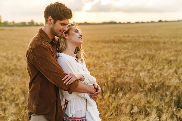 在乡村金色的田野里 年轻的高加索人美丽的夫妻拥抱在一起的景象 — 图库照片