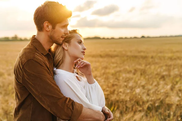 在乡村金色的田野里 年轻的高加索人美丽的夫妻拥抱在一起的景象 — 图库照片