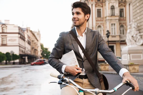 自転車で新聞を持って屋外で若い楽観的なビジネスの男のイメージ — ストック写真