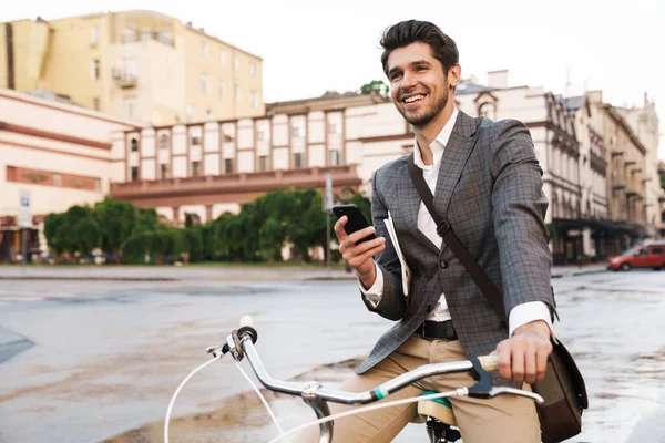 Imagem Empresário Bonito Feliz Jaqueta Sorrindo Usando Celular Bicicleta Rua — Fotografia de Stock
