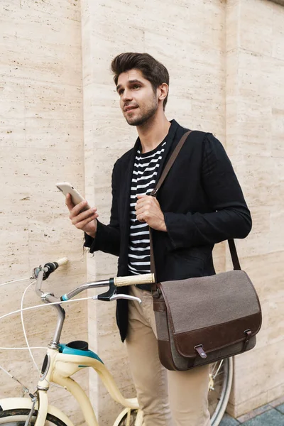 Dışarıdaki bir iş adamının bisiklet üzerinde cep telefonu kullanması.