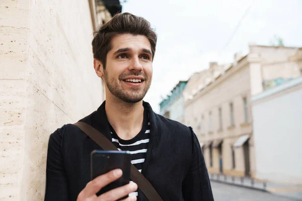 Imagen Hombre Guapo Feliz Sonriendo Usando Teléfono Celular Mientras Apoya — Foto de Stock