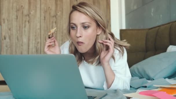 Μια Χαρούμενη Συναισθηματική Νεαρή Γυναίκα Τρώει Πίτσα Ενώ Βλέπει Κάτι — Αρχείο Βίντεο