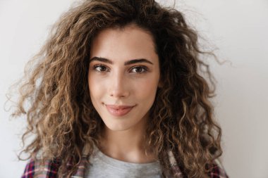 Beyaz arka planda izole edilmiş kamerada poz verirken gülümseyen güzel bir kadının fotoğrafı.