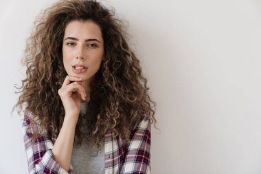 Kafası karışmış güzel bir kadının beyaz arka planda izole bir şekilde kameraya bakıp poz vermesi.