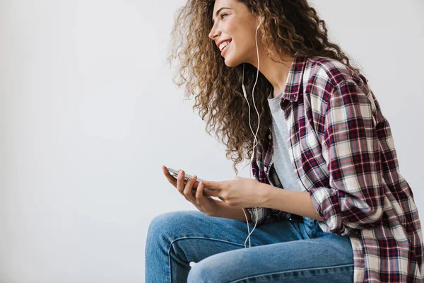 Foto Una Joven Sonriente Usando Teléfono Celular Auriculares Mientras Está —  Fotos de Stock