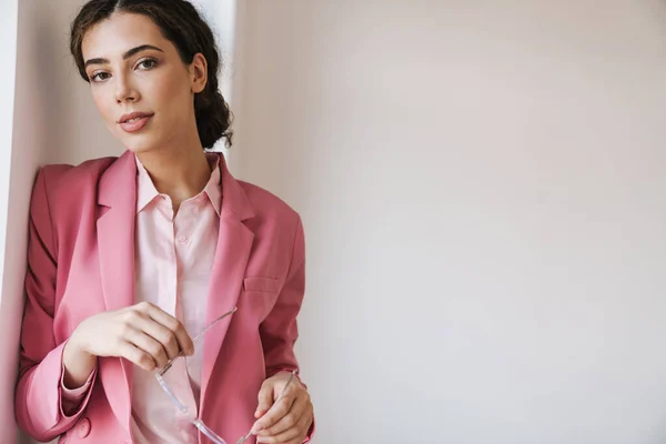 Foto Hermosa Mujer Complacida Chaqueta Rosa Sosteniendo Anteojos Mientras Posa — Foto de Stock