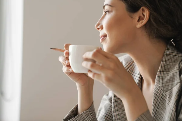 Foto Cerca Sonriente Morena Bebiendo Café Mientras Trabaja Una Oficina — Foto de Stock