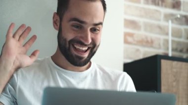 Mutlu genç bir adam içeride oturan dizüstü bilgisayarını kullanan biriyle konuşuyor.