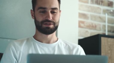 Çekici genç bir adam içeride oturan dizüstü bilgisayarını kullanan biriyle konuşuyor.