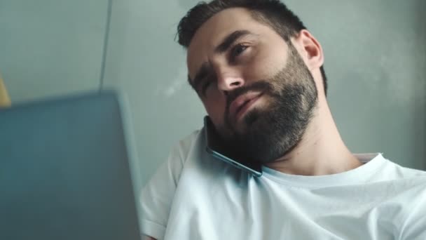 Ein Gutaussehender Junger Mann Telefoniert Mit Seinem Laptop Während Drinnen — Stockvideo