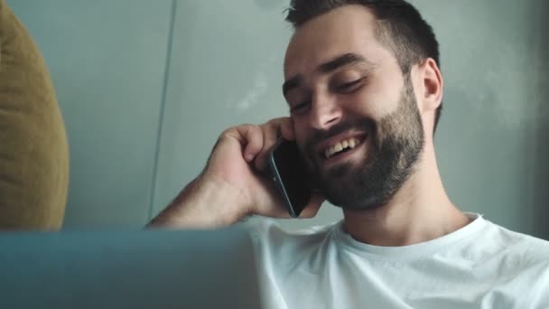 Giovane Uomo Contento Sta Parlando Telefono Mentre Usa Suo Computer — Video Stock
