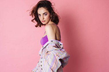 Kızıl saçlı baştan çıkarıcı kadın görüntüsü pembe arka planda izole edilmiş poz veren ve kameraya bakan.